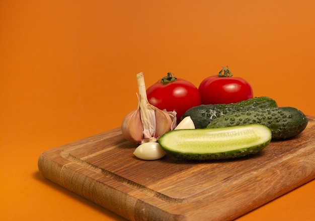 Tomates de pepino en rodajas y ajo en una tabla de cortar de madera Tomates con colas de caballo verdes