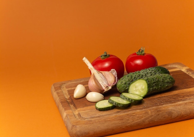 Tomates de pepino en rodajas y ajo en una tabla de cortar de madera Tomates con colas de caballo verdes