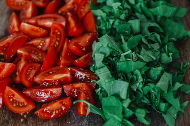 Tomates picados y espinacas de color verde brillante en la mesa rústica de madera