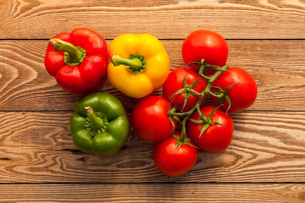 Tomates y pimientos sobre un fondo de madera