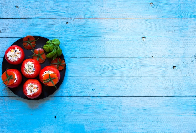 Tomates recheados com queijo e vegetais diferentes em uma mesa de madeira