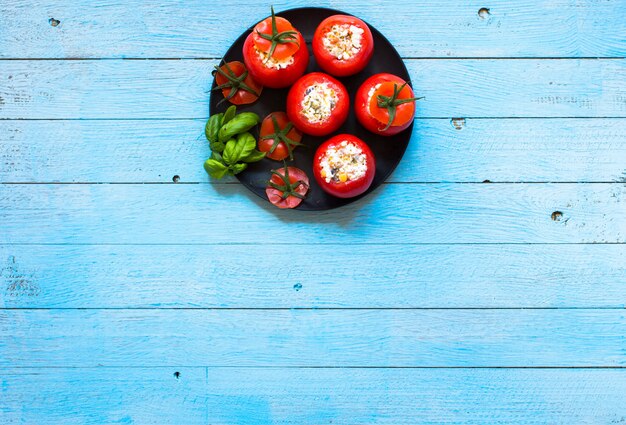 Tomates recheados com queijo e vegetais diferentes em uma mesa de madeira