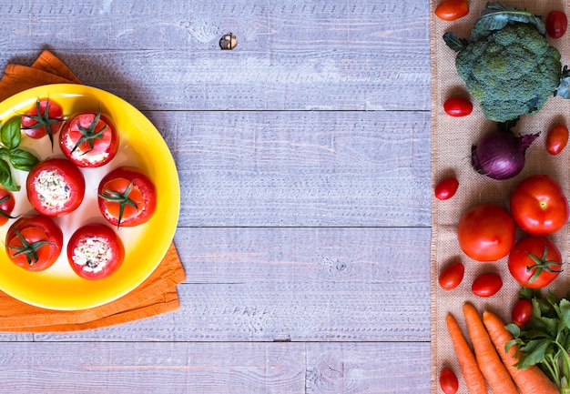 Tomates recheados com queijo e vegetais diferentes, sobre um fundo de madeira,