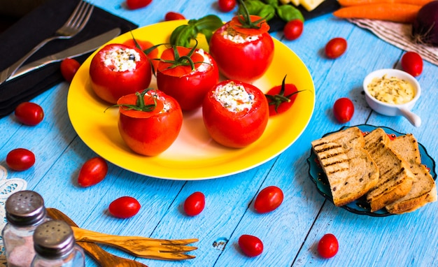 Tomates recheados com queijo e vegetais diferentes, sobre um fundo de madeira,