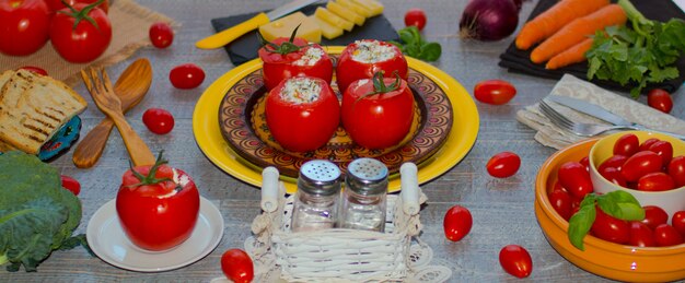 Tomates recheados com queijo e vegetais diferentes, sobre um fundo de madeira,