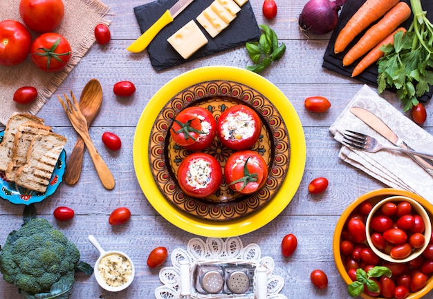 Tomates rellenos con queso y diferentes verduras en una mesa de madera