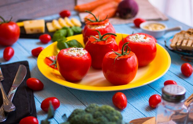 Tomates rellenos con queso y diferentes verduras, sobre una mesa de madera,