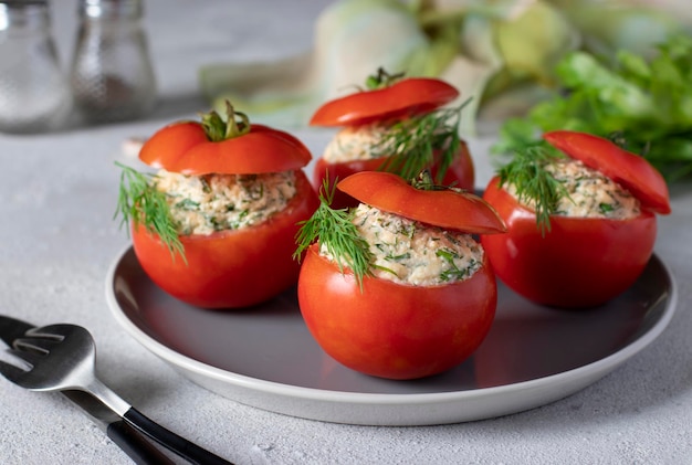 Tomates rellenos con queso, eneldo y ajo en un plato gris sobre un fondo claro