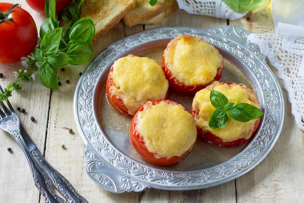 Tomates rellenos Tomates horneados con queso y pollo en una mesa de cocina de madera