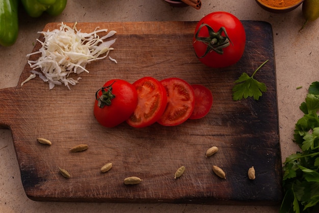 Tomates en rodajas para cocinar comida vegetariana saludable en el tablero en la mesa de la cocina