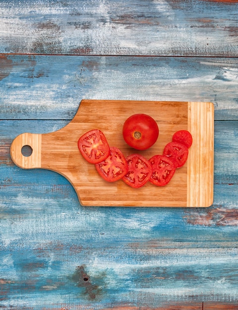 Tomates en rodajas en la tabla de cortar en la mesa