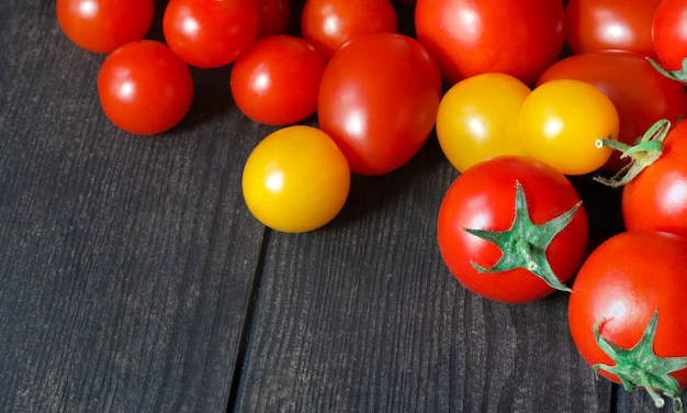 Tomates rojos y amarillos en una mesa oscura, tomates frescos en una vieja mesa de madera, cultivo de verduras, comida sana, comida vegetariana, venta de tomates