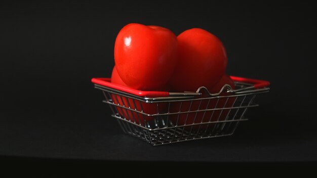 Tomates rojos en una canasta de supermercado muchos