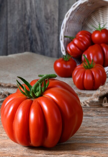 Tomates rojos crudos maduros sobre mesa de madera rústica