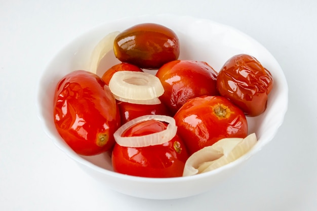 Tomates rojos en escabeche en un plato blanco.