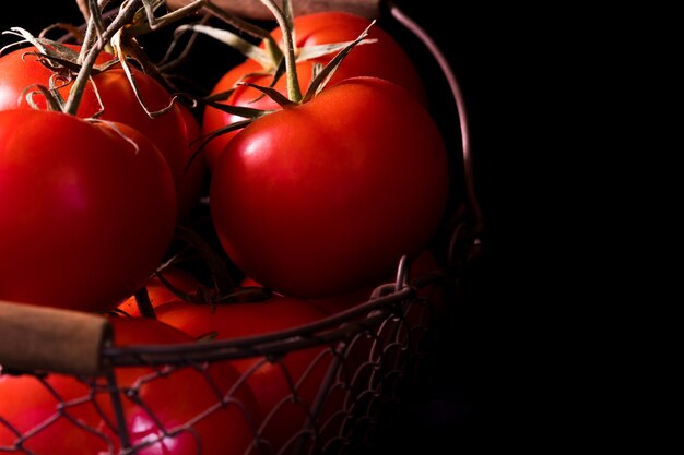 Foto tomates rojos grandes en negro en claro oscuro listos para cocinar