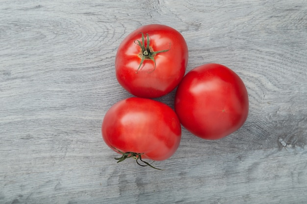 Tomates rojos maduros colocados sobre la mesa de madera gris