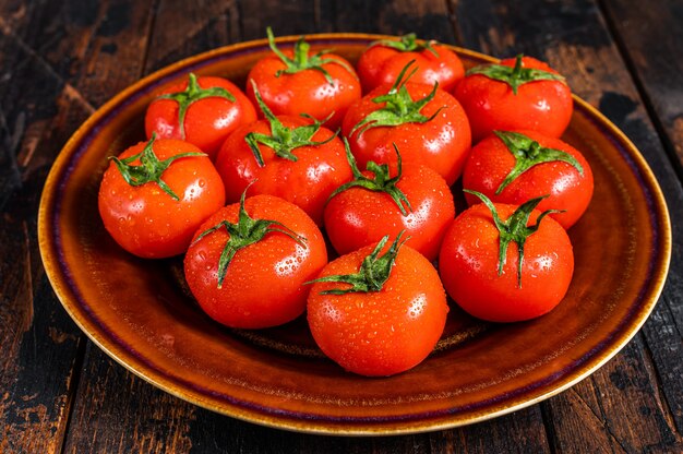 Tomates rojos maduros en placa rústica