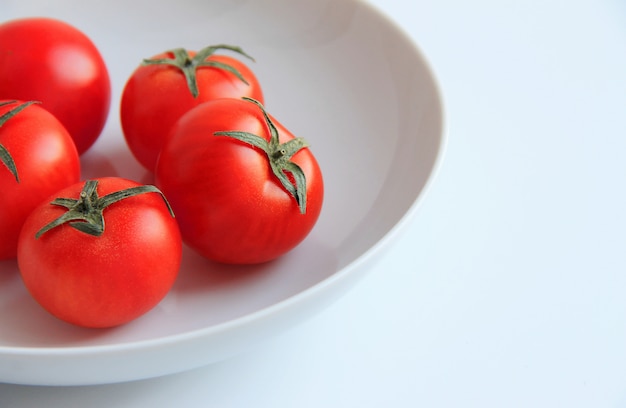 Tomates rojos en un plato blanco sobre un fondo blanco