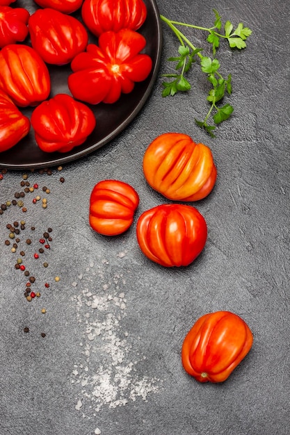 Tomates rojos en el plato y en la mesa Ramita de perejil pimienta de Jamaica y sal