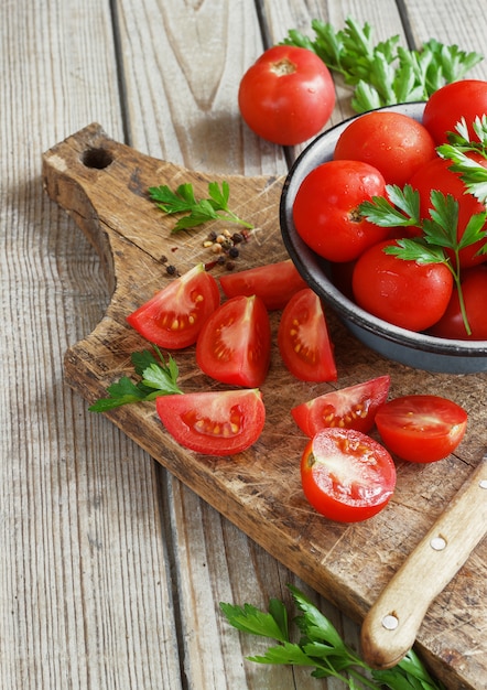 Tomates rojos sobre una plancha de madera con perejil. estilo rústico