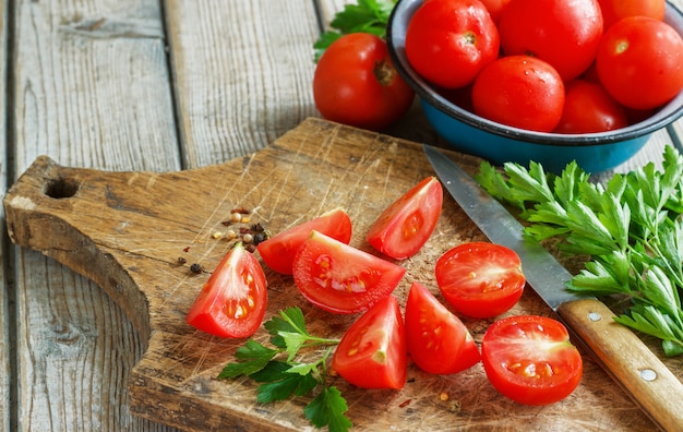 Tomates rojos sobre una plancha de madera con perejil. estilo rústico