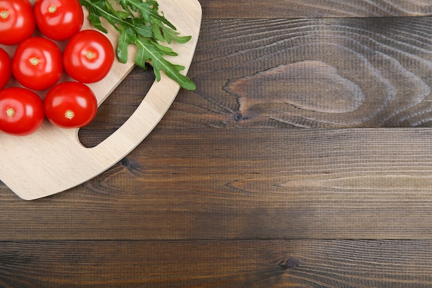 Tomates rojos sobre una superficie de madera oscura.