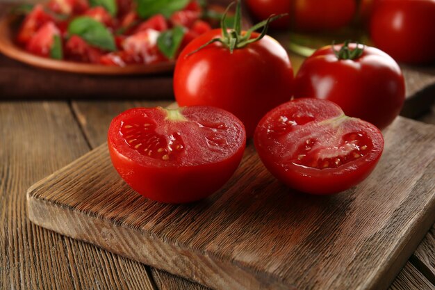 Tomates rojos en la tabla de cortar sobre fondo de madera