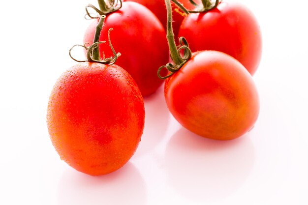 Tomates Roma orgânicos em fundo branco.