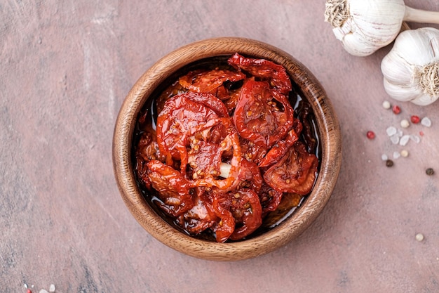 Tomates secados al sol en cuenco de madera Tomates secos con aceite de oliva, romero, sal, hierbas y ajo