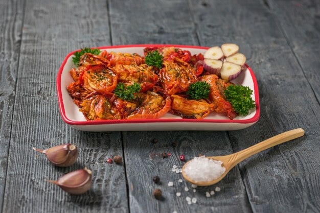 Tomates secos con ajo y una cuchara de madera con sal marina grande sobre una mesa de madera