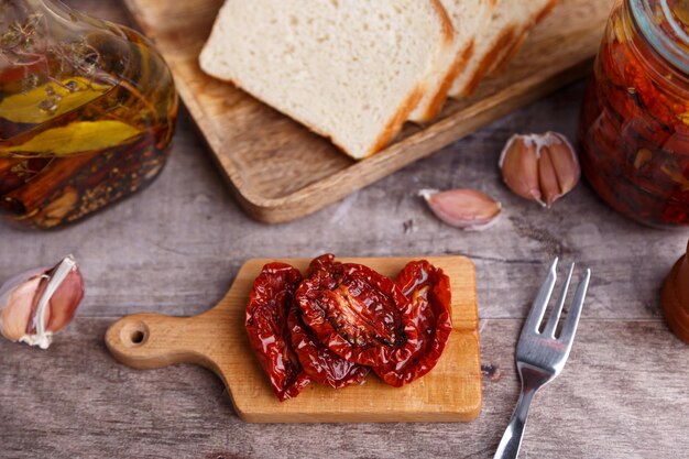 Tomates secos al sol en aceite de oliva en una mini tabla con pan casero en un estilo rústico cocina casera tradicional enfoque selectivo de primer plano