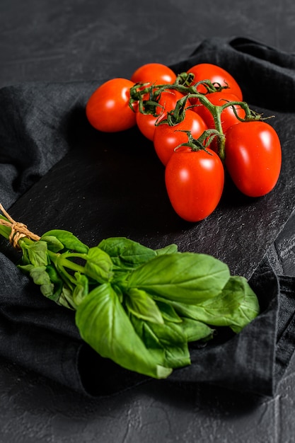 Tomates sobre un fondo negro con albahaca. Vista superior.