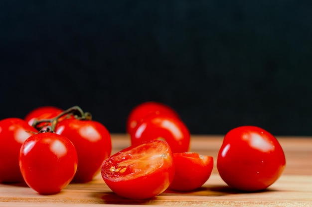 Tomates sobre uma mesa de madeira com fundo preto