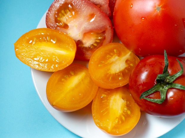 Tomates suculentos fatiados de diferentes variedades em um prato Tomates laranja com efeito de estufa Comida vegetariana Ainda vida de vegetais