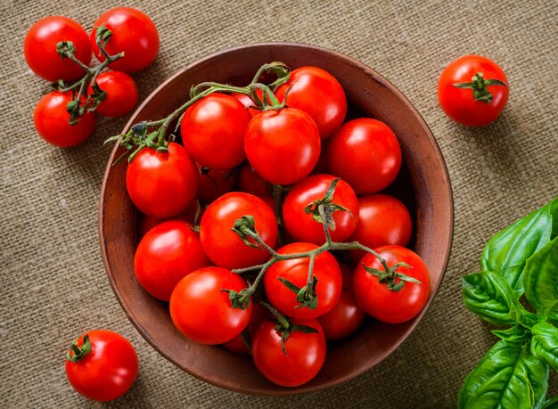 Tomates en un tazón con albahaca sobre fondo de tela