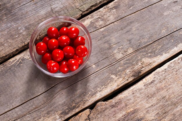 Tomates en tazón de vidrio Tomates en fondo de madera marrón Verduras jugosas frescas Ingrediente para una ensalada