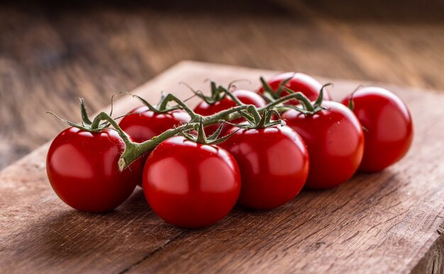 Tomates. Tomates cherry. Tomates de cóctel sobre tabla de madera.