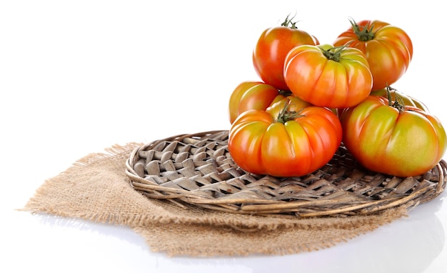 Tomates verdes en soporte de mimbre aislado en blanco