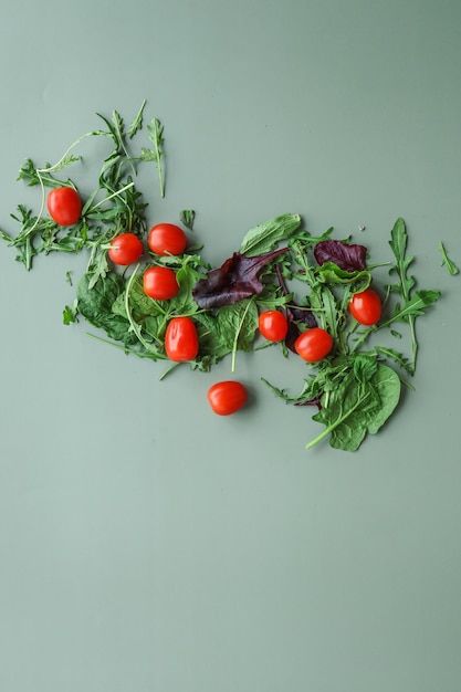 Tomates y verduras para ensalada sobre un fondo verde Concepto de comida plana