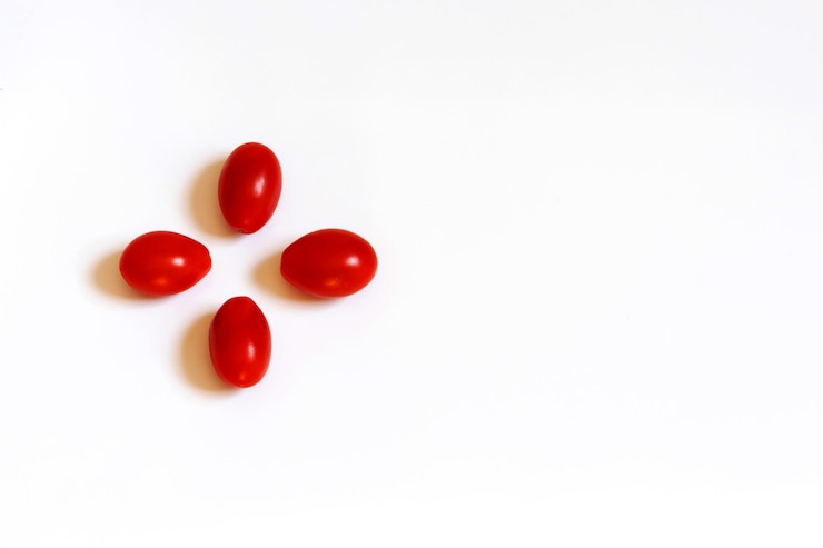 Foto tomates vermelhos de cereja em um fundo plano branco os tomates estão posicionados como pétalas de uma flor
