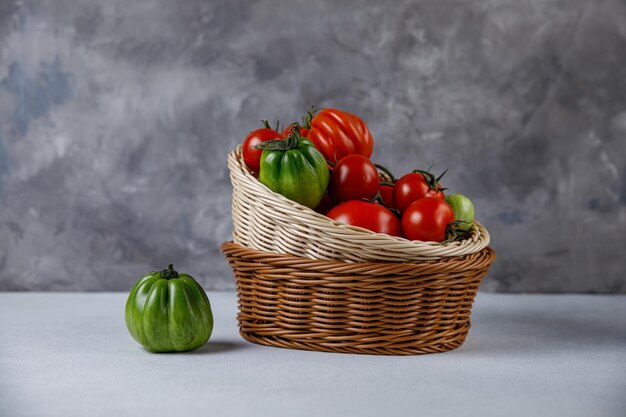 Tomates vermelhos e verdes em uma cesta em um fundo úmido