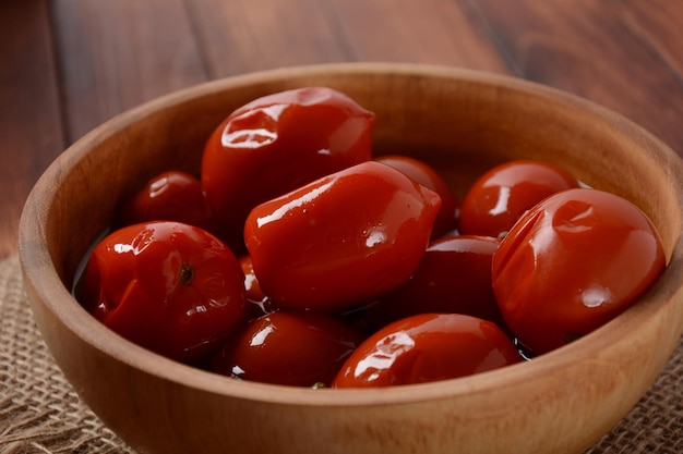 Tomates vermelhos em conserva em tigela sobre fundo de madeira Estilo rústico