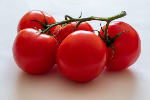 Tomates vermelhos em um galho em um fundo branco