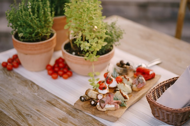 Tomates vermelhos em uma mesa com uma tábua e flores em vasos