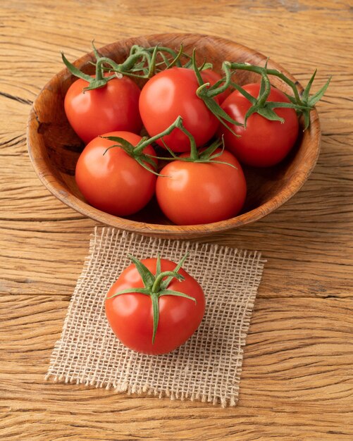 Tomates vermelhos em uma tigela sobre a mesa de madeira