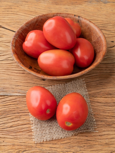 Tomates vermelhos em uma tigela sobre a mesa de madeira