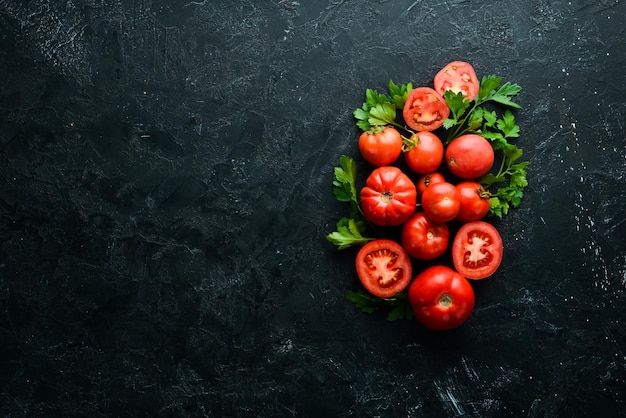 Tomates vermelhos frescos no fundo de pedra preta Verdes Vista superior Espaço livre para o seu texto