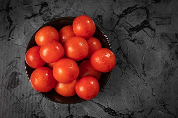 Foto tomates vermelhos grandes em uma placa preta, em uma mesa de granito