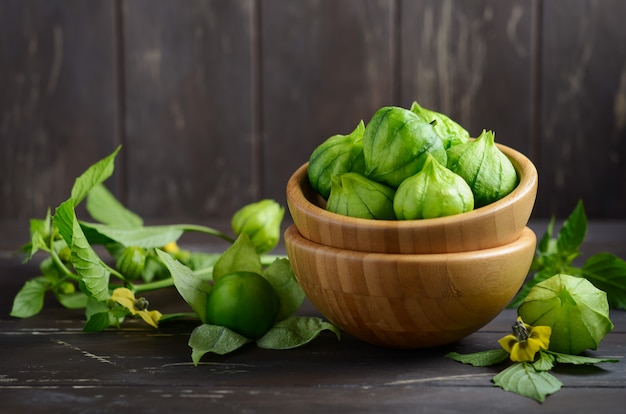 Tomatillos verdes orgánicos frescos con una cáscara en la tabla de madera rústica.